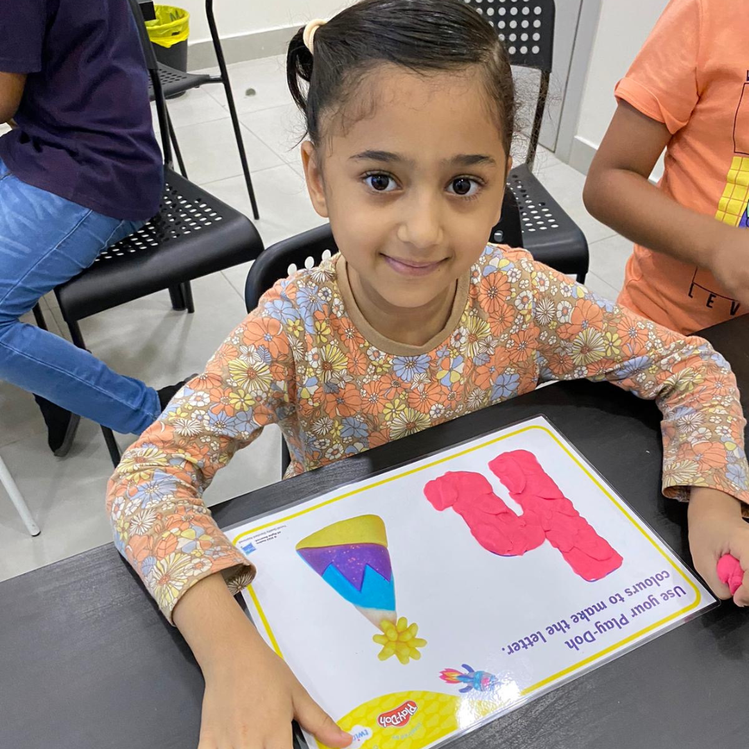 Young student making their letter shapes with play dough