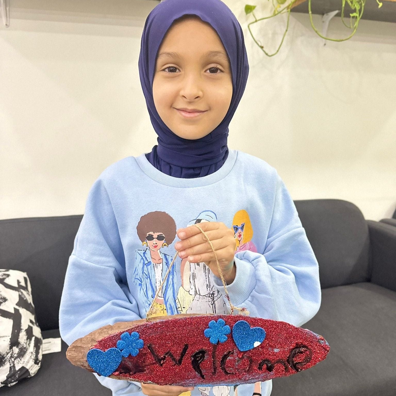 We use crafts to make lessons enjoyable for children. Young girl holding a welcome sign for her unit on 'My Home'