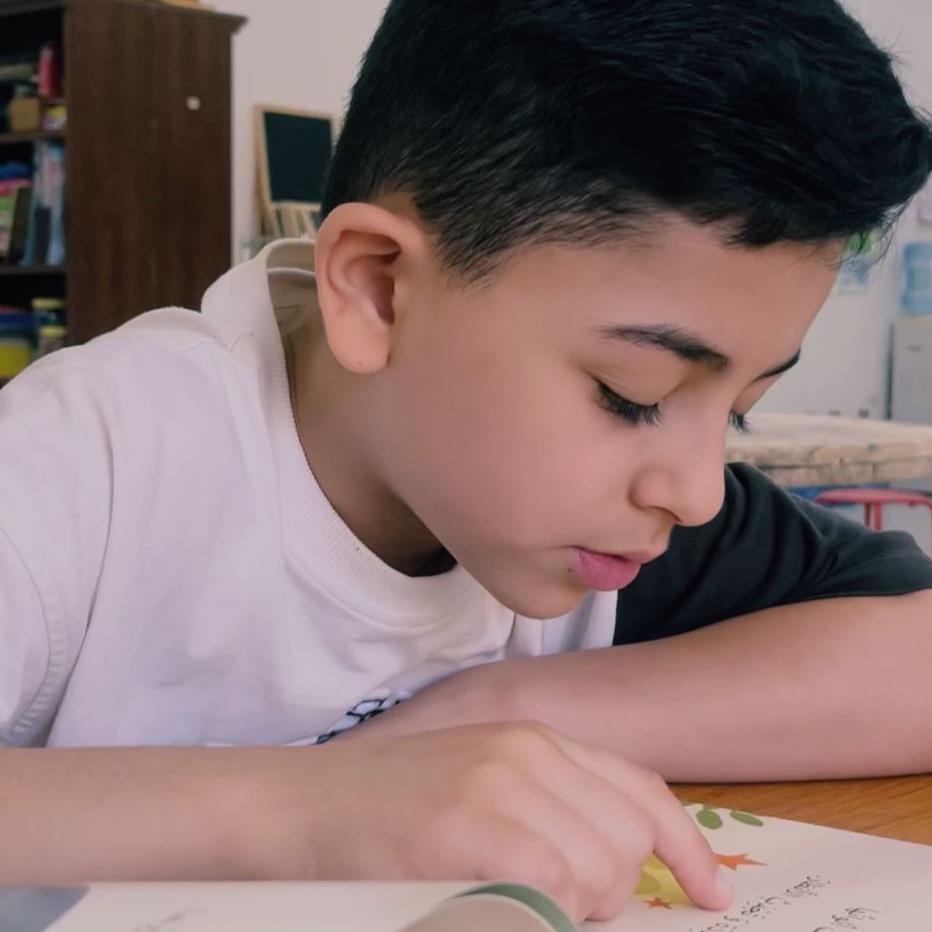 Primary schooler reading an Arabic book, learning Arabic through stories they love