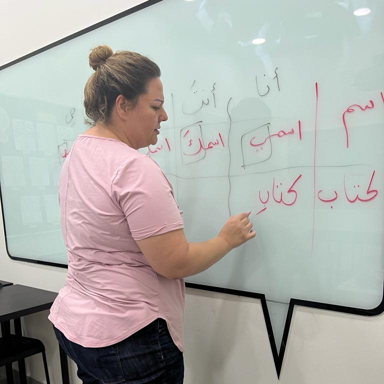 Adult writing Arabic on a board