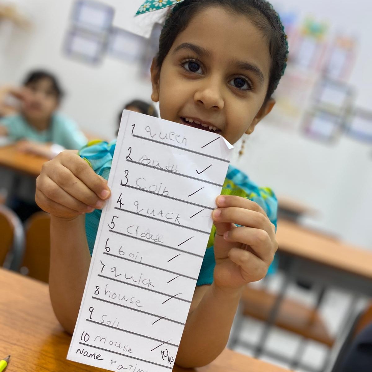 Primary school student holding their spelling test up and showing that they got 100% 