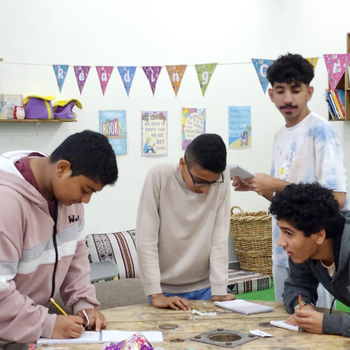 4 teenaged boys collaborating on a group project to learn English, this is in preparation for university